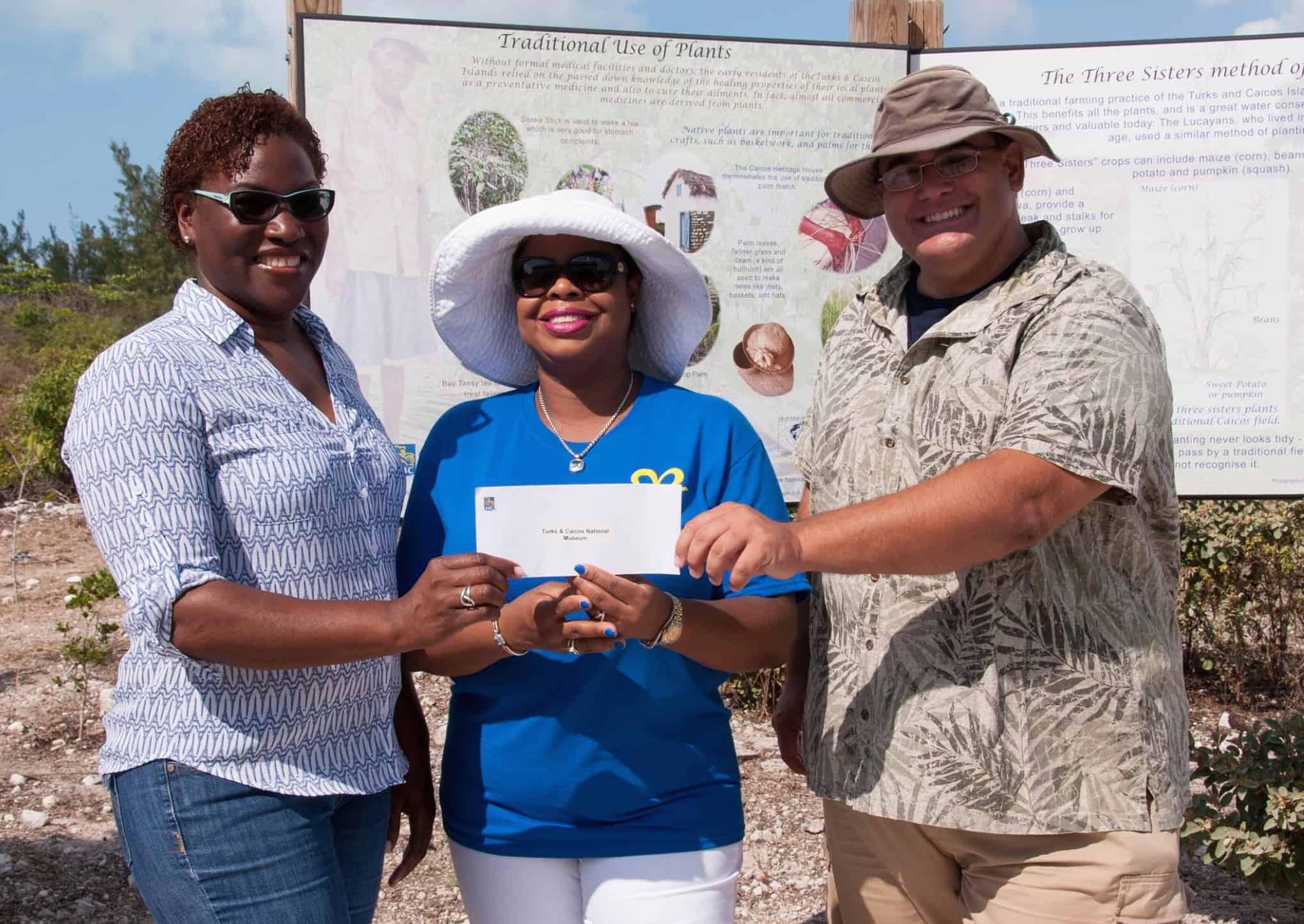 Candianne Williams (Manager, Turks and Caicos National Museum, Providenciales) and Bryan Naqqi Manco (DECR and TCNM) are presented with a cheque from Sanfra Foster (Manager, Royal Bank of Canada, Providenciales) [centre]