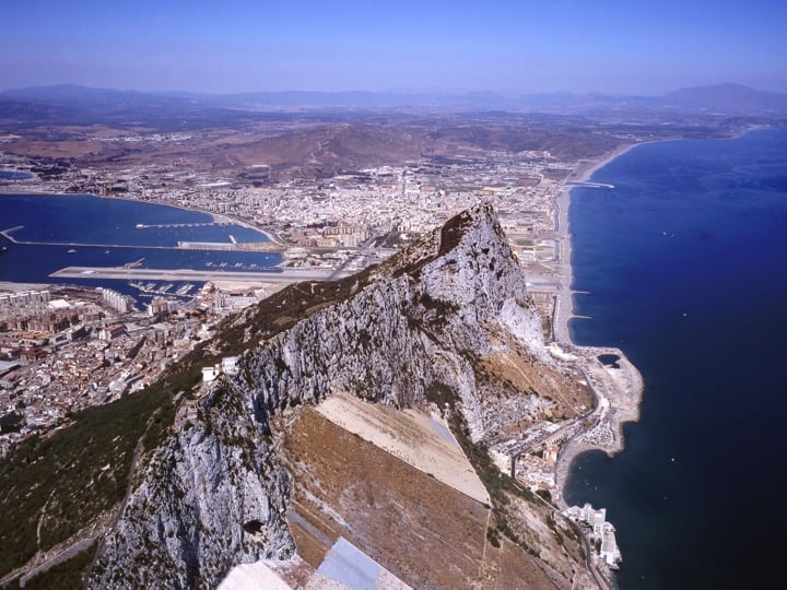 Looking to the north, with steep eastern slopes to the right, the town to the left, and the airport runway and Spain beyond the Rock;Copyright: HM Government of Gibraltar (HMGOG) / Gibraltar Ornithological & Natural History Society (GONHS).